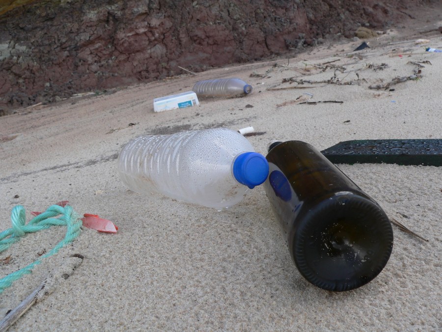 Garrafas de vidro e plástico na praia.